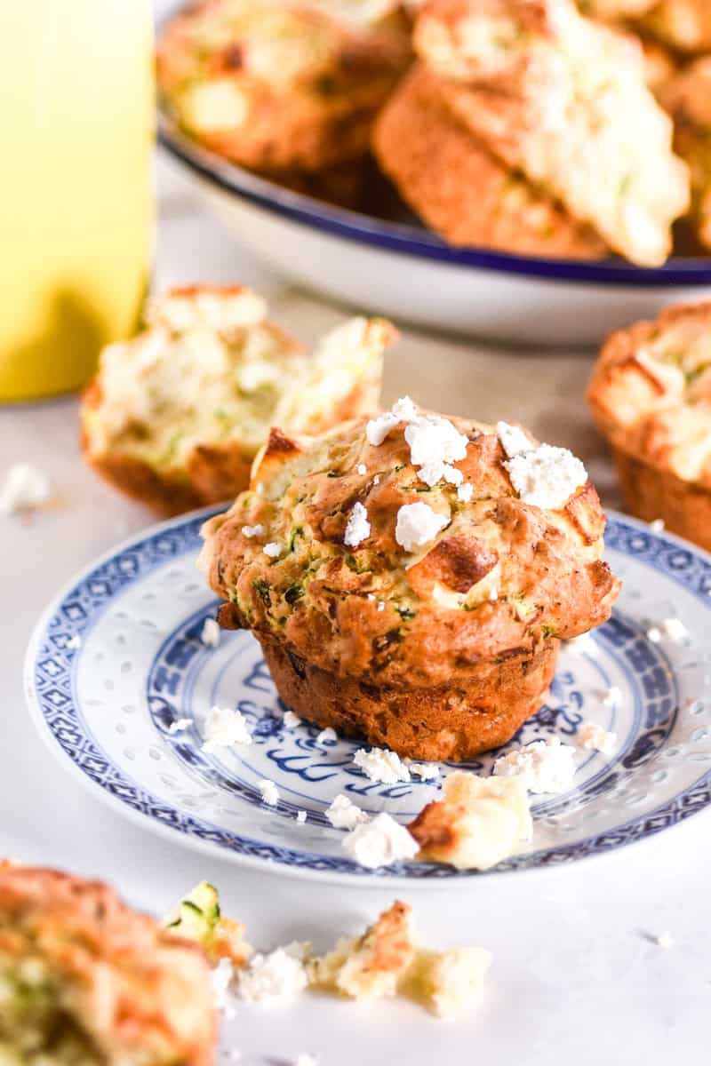 Image shows a muffin on a white and blue plate with feta crumbled over the muffin.
