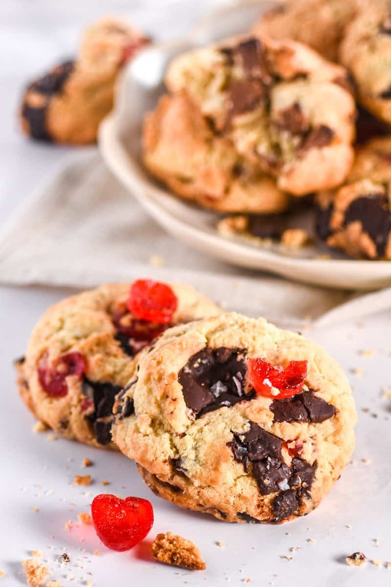 Image showing two cookies in front of a plate filled with cookies. 