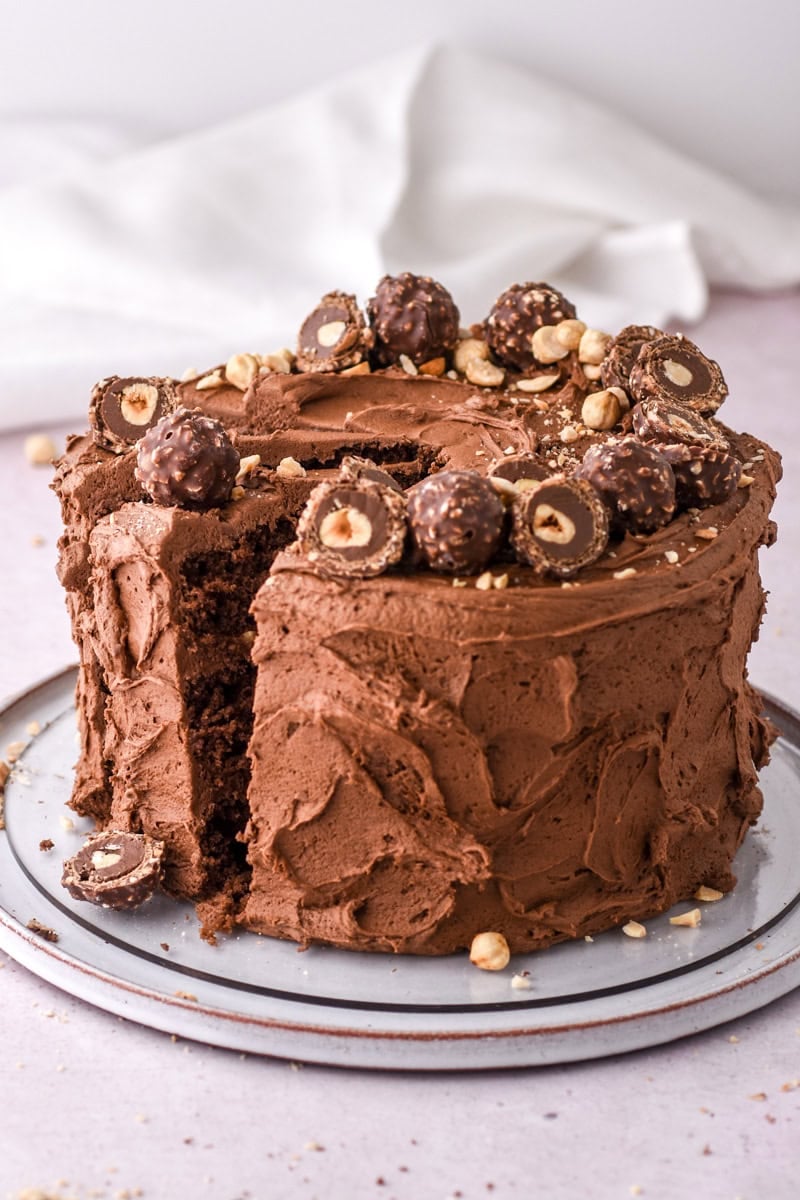 Image shows cake on a cake plate on a counter, there is a folded napkin in the background. 