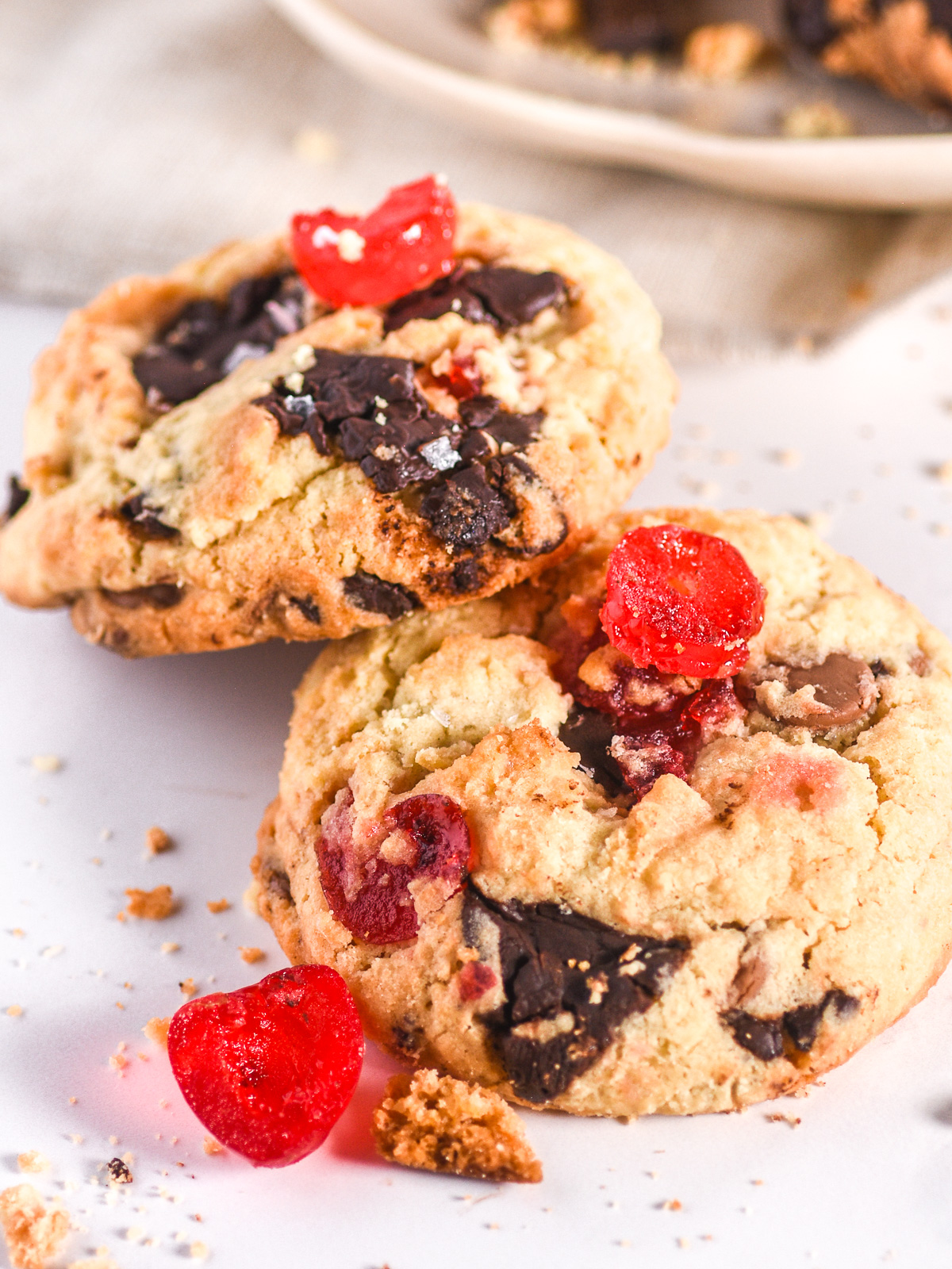 Two cookies shown resting on each other, there is a plate of cookies in the background.