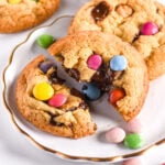Smarties cookies shown on a white plate with smarties scattered around.