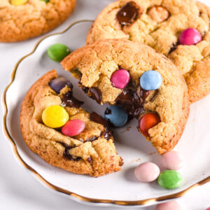 Smarties cookies shown on a white plate with smarties scattered around.