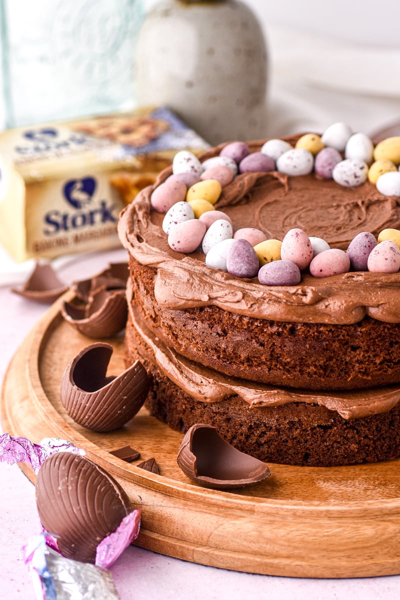 Image shows a chocolate Easter cake with chocolate eggs scattered around.
