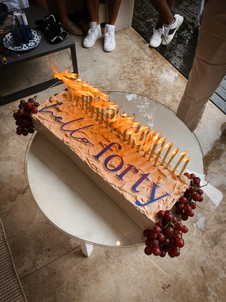 An image showing a slab birthday cake decorated with a Hello Forty cake topper and candles.