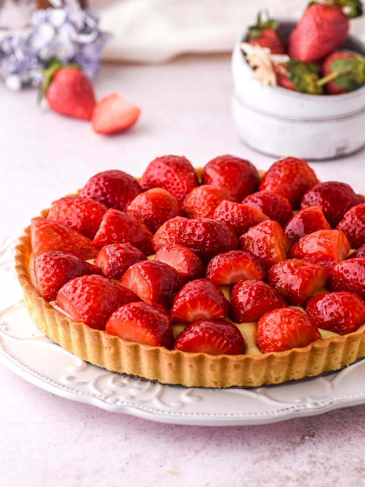 Image shows a tart filled with custard and decorated with sliced strawberries.
