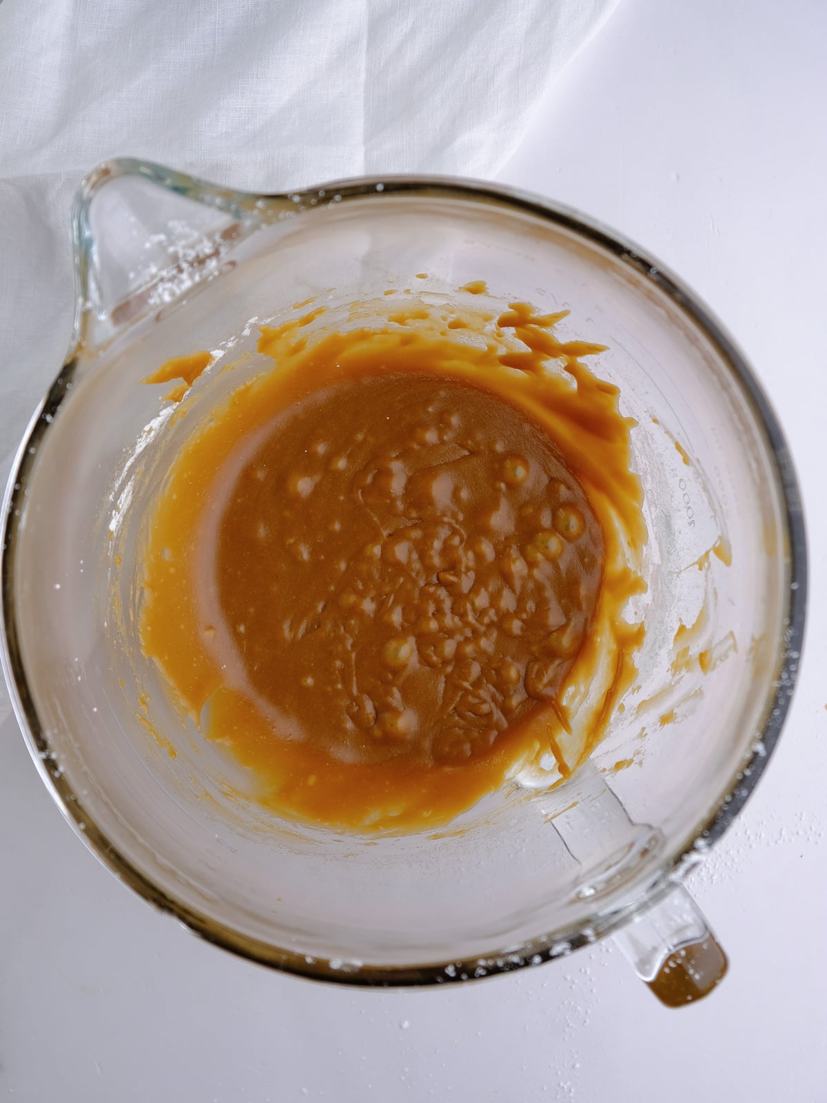 Image shows step 2 of how to make caramel glaze: whisking in the powdered sugar.