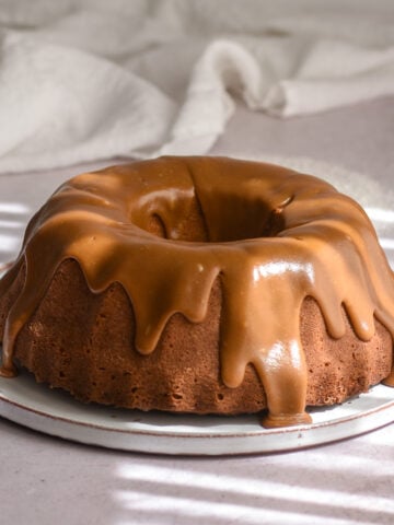 Apple Pecan Cake with Caramel Glaze shown on a flat cake plate.