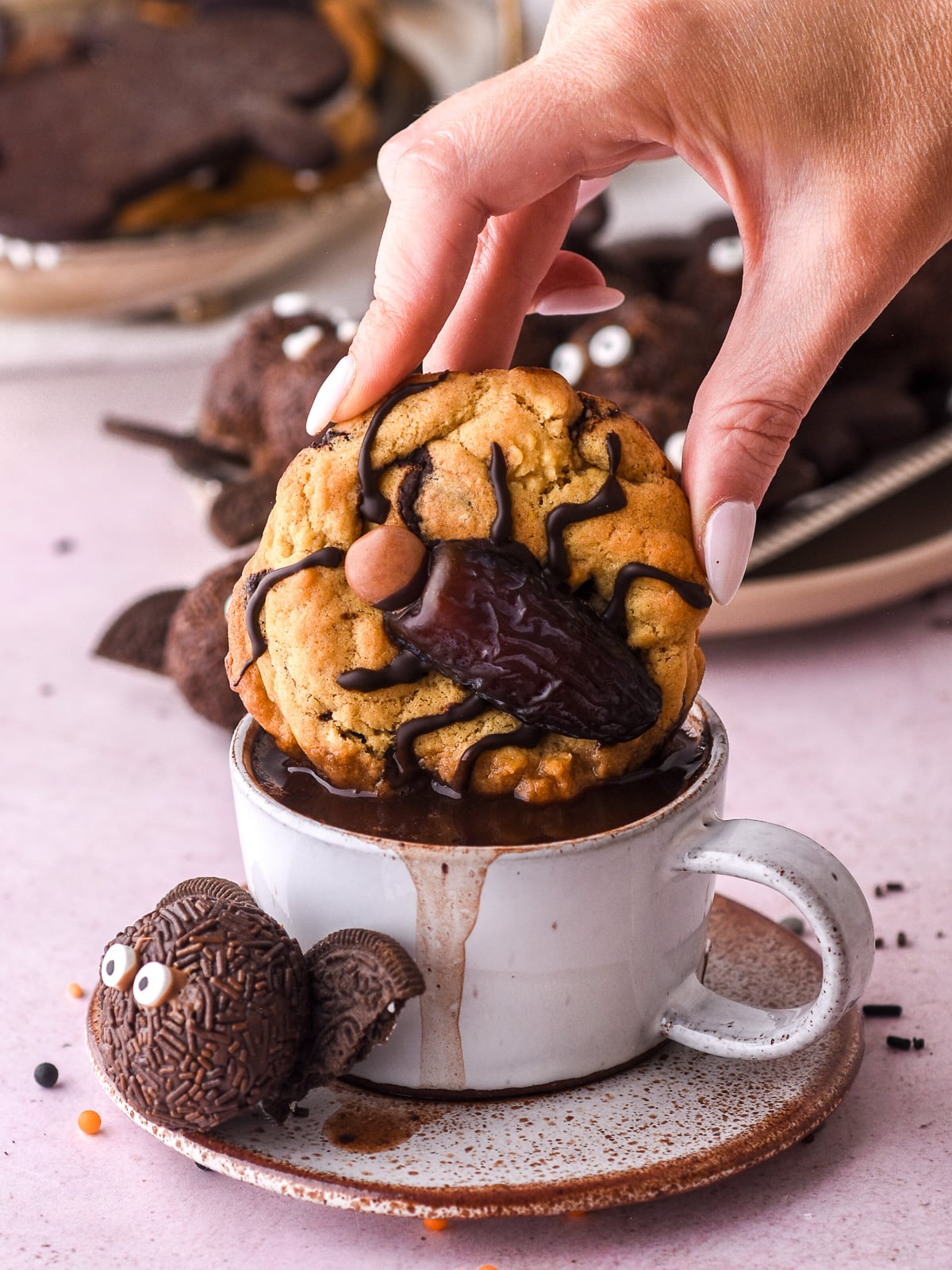 Halloween Cockroach Chocolate Chip Cookie shown being dipped into a cup of hot chocolate.