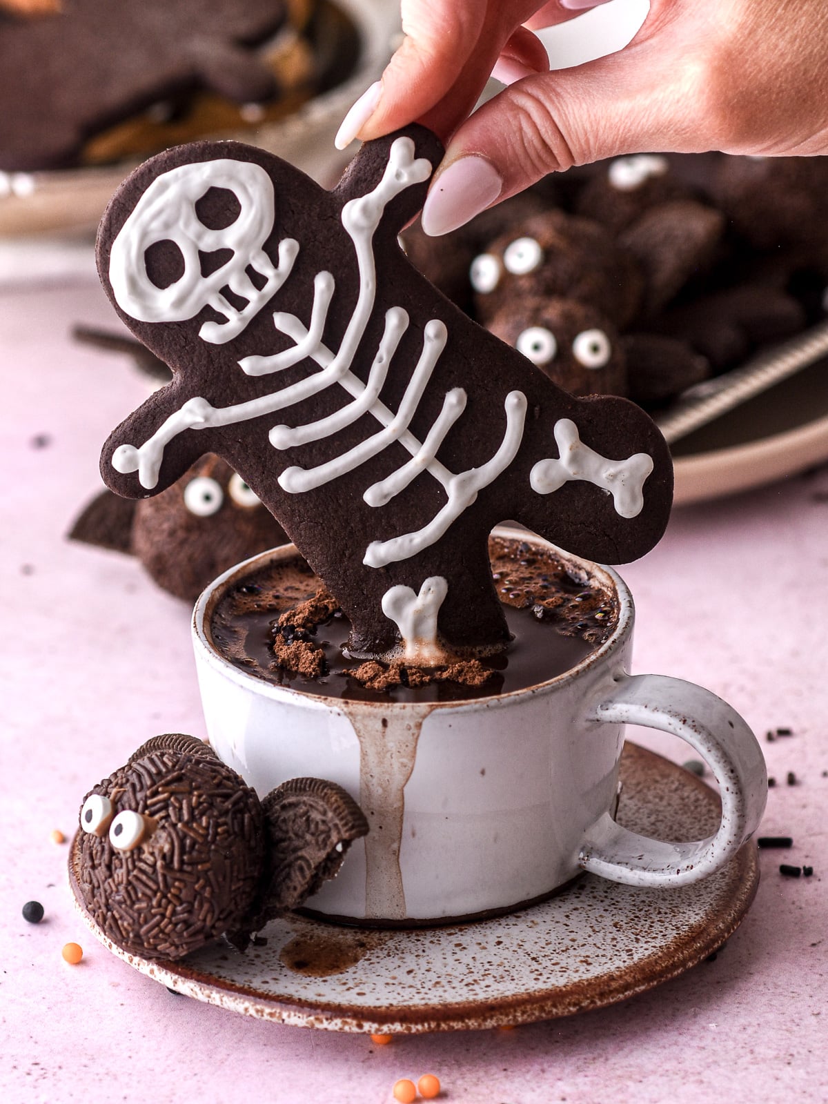 Halloween Gingerbread Men Skeletons shown being dunked into a small teacup filled with hot chocolate.
