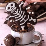 Halloween Gingerbread Men Skeleton cookie shown dipped into a cup of hot chocolate.