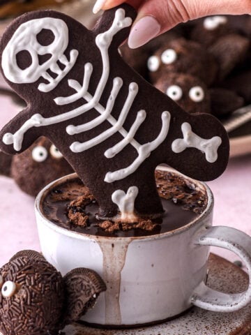 Halloween Gingerbread Men Skeleton cookie shown dipped into a cup of hot chocolate.