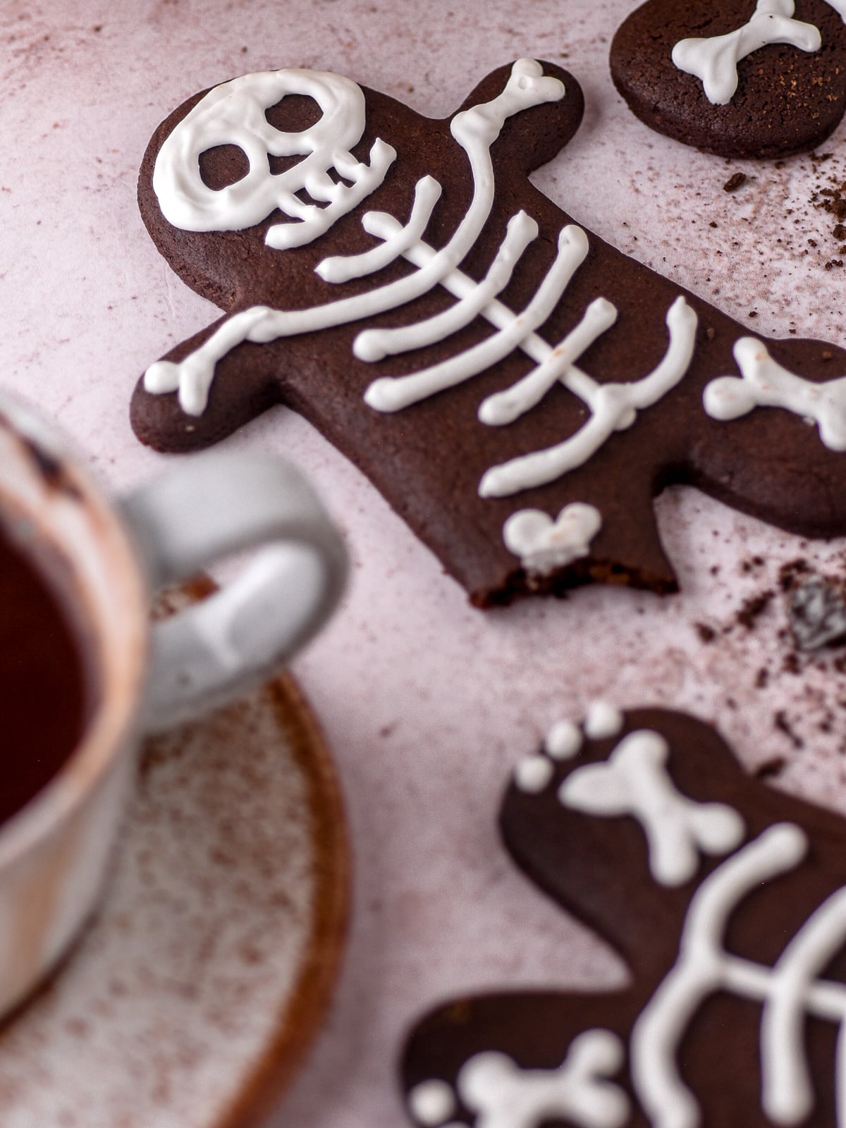 Halloween Gingerbread Men Skeletons shown with a leg missing on a kitchen counter next to crumbs and other cookies.