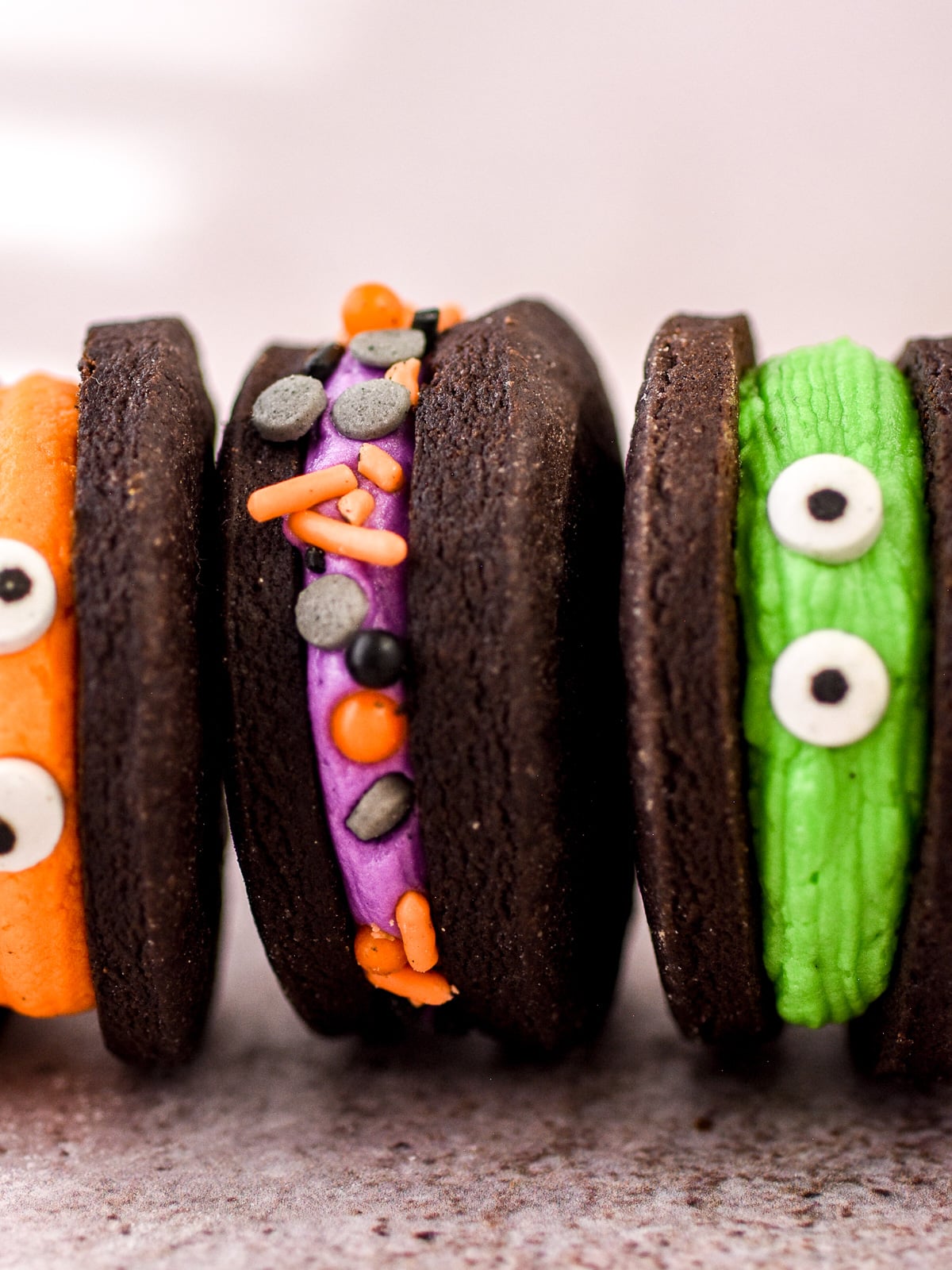 Halloween Monster Cookie Sandwiches shown in a horizontal line next to each other.