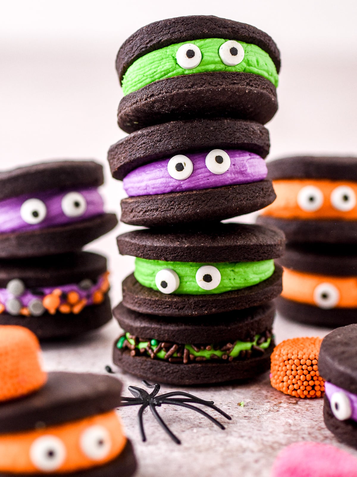 Halloween Monster Cookie Sandwiches filled with different colored buttercream showed stacked on top of one another.